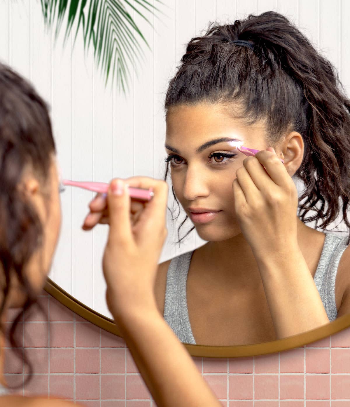 A person using Lemon Lavender Light Up Tweezer LED spotlight tweezers to groom their eyebrows in front of a mirror.