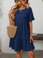A woman in a Suhkasana Loose Casual Short-Sleeve Dress, paired with a woven straw handbag, sunglasses, bracelets, necklaces, and a hat—a chic look for stylish summer days.