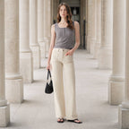 A woman wearing a gray tank top and Faire Off White Mid Rise Straight Pants with patch pockets, holding a black handbag.