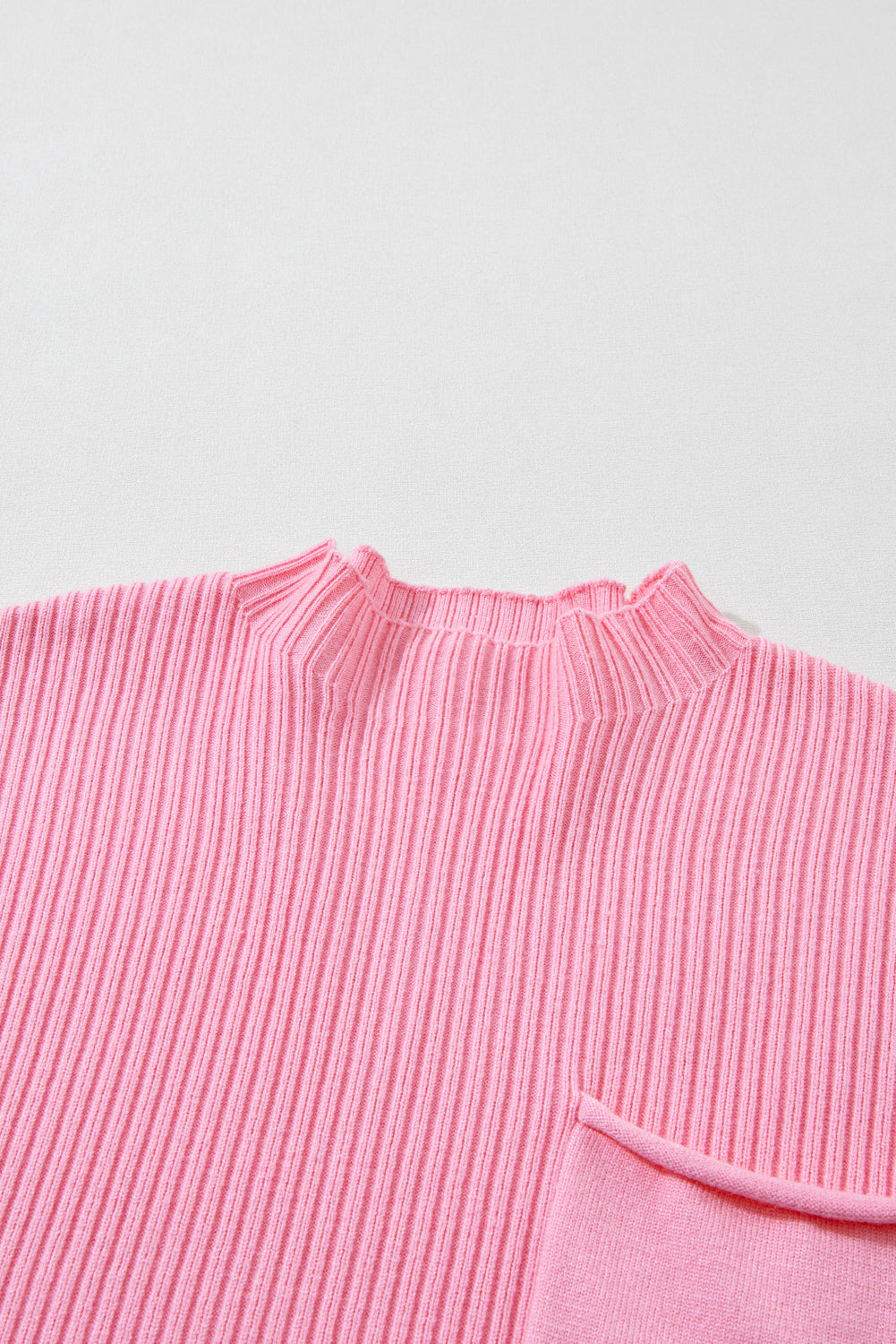 Close-up of the Patch Pocket Ribbed Knit Short Sleeve Sweater by Shewin, a versatile pink knit sweater with a round neckline and pocket, set against a light gray background.