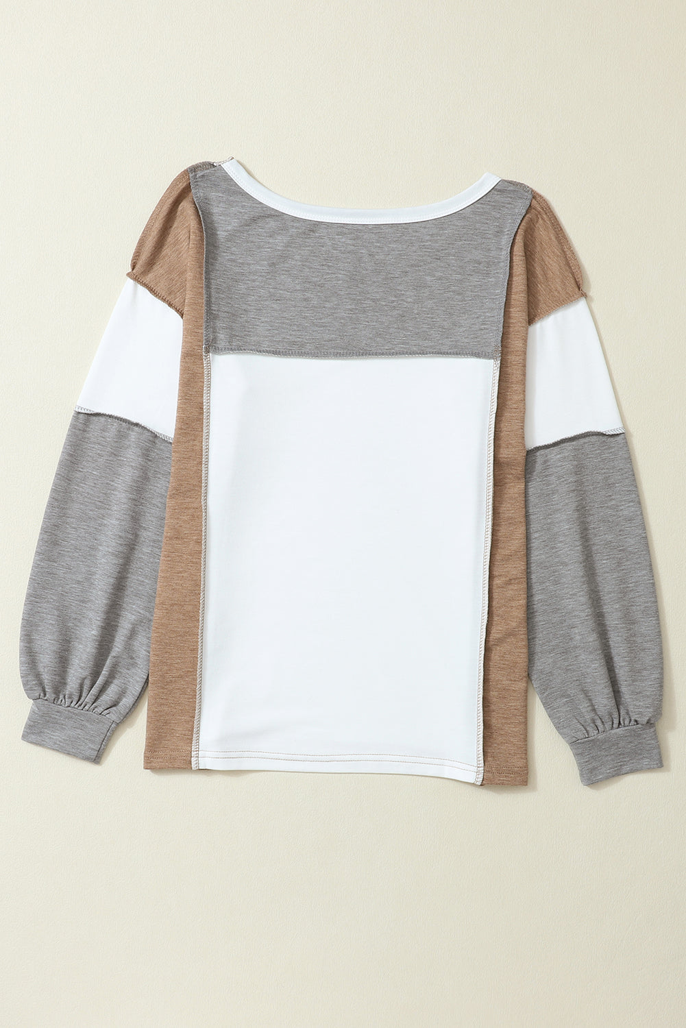 Back view of the Shewin Khaki Color Block Exposed Seam Long Sleeve Top, featuring tan, gray, and white patchwork sections. This shirt comes with elastic cuffs and a round neckline.