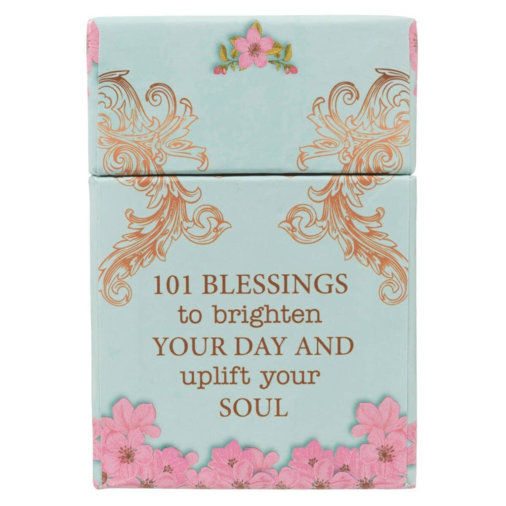 The Box of Blessings Promises for Women by Christian Art Gifts features a light blue box adorned with gold decorative swirls, pink flowers, and the words "101 blessings to brighten your day and uplift your soul." Inside are inspiring Bible verse cards highlighting God's promises especially for women.