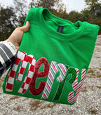 Faire Green Merry Sequin Christmas Sweatshirt in bright green with “Merry” appliqued on the front in red, white, and green candy cane-patterned and sequined fabric.