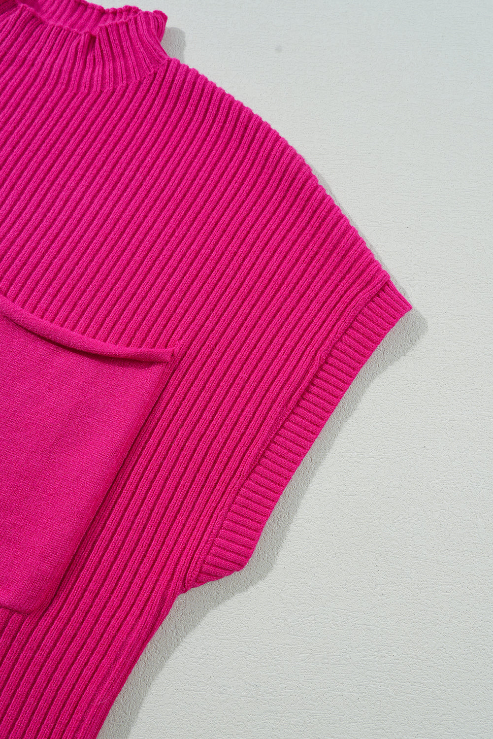 Close-up of a Shewin Patch Pocket Ribbed Knit Short Sleeve Sweater, in pink, against a light gray background.