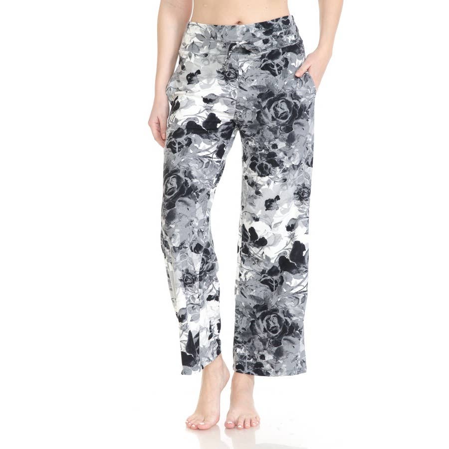 A person wearing Leggings Depot Buttery Soft Print Pajama Pants, featuring a black and white floral pattern and an elastic waistband, stands barefoot against a white background.