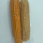 Two whole cobs, one orange and one light brown, are sealed side by side in a clear pouch. Amish Country Popcorn's Twin Microwave Popcorn Cobs are perfect for easy popping. Set against a plain white background.