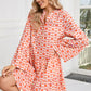 A woman wearing a Shewin Orange Floral Button V Neck Bell Sleeve Mini Dress sits on a stool in a bright room.