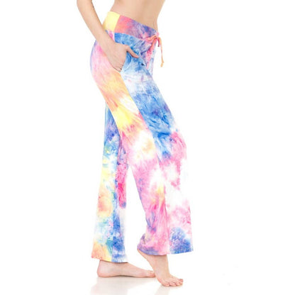 A person wears Leggings Depot Buttery Soft Print Pajama Pants, featuring a vibrant tie dye pattern, elastic waistband, and pockets, standing barefoot against a white background.