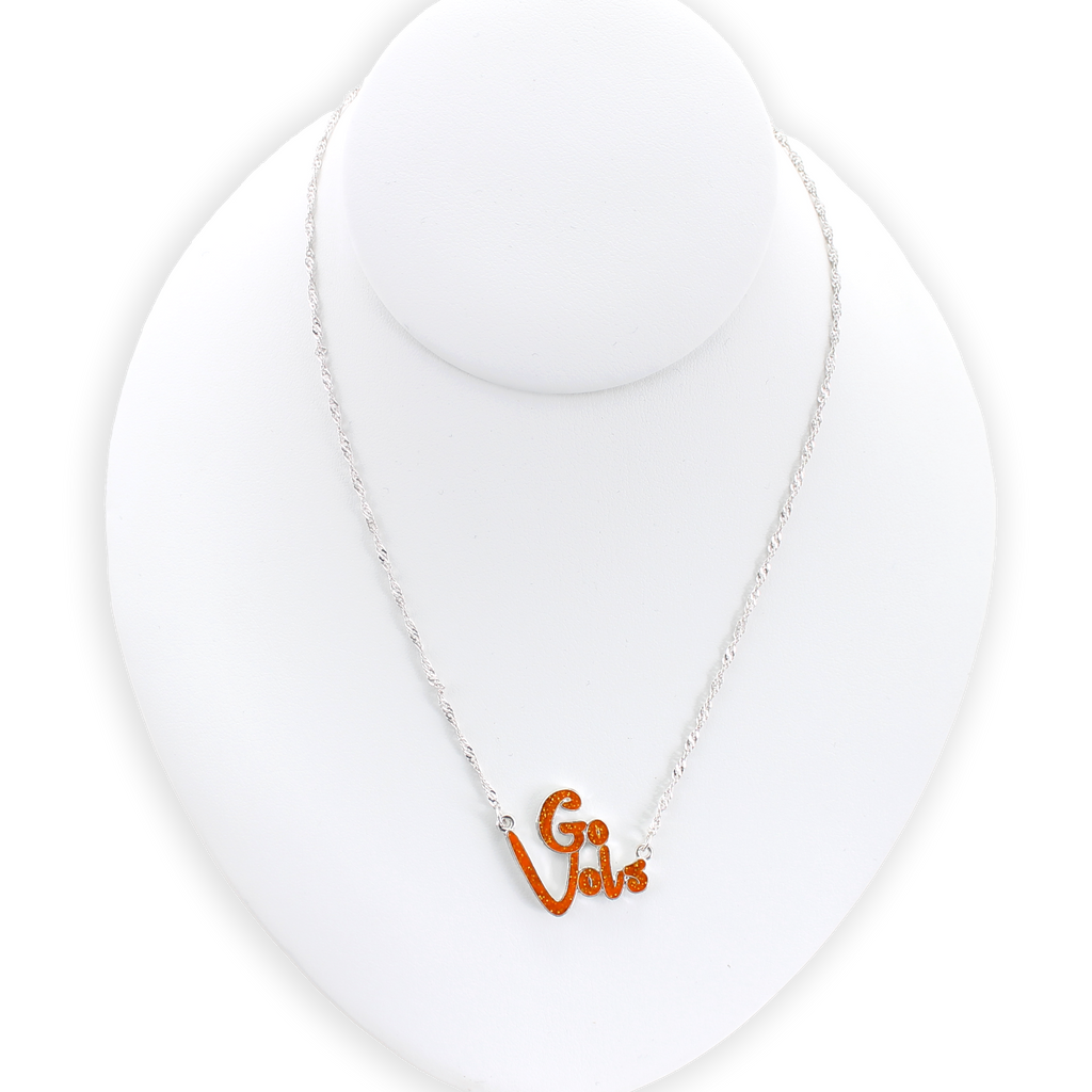 The Tennessee Slogan Necklace by Seasons Jewelry features a sparkling "Go Vols" charm in vibrant orange glitter enamel, displayed on a white jewelry bust against a plain background—the perfect game day accessory for any fan.