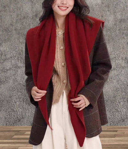 A woman wearing a brown plaid blazer, beige sweater, white pants, and the JC Sunny Fashion Cashmere-Blend Knit Triangle Shawl with Cross-Front Design stands against a textured gray background.