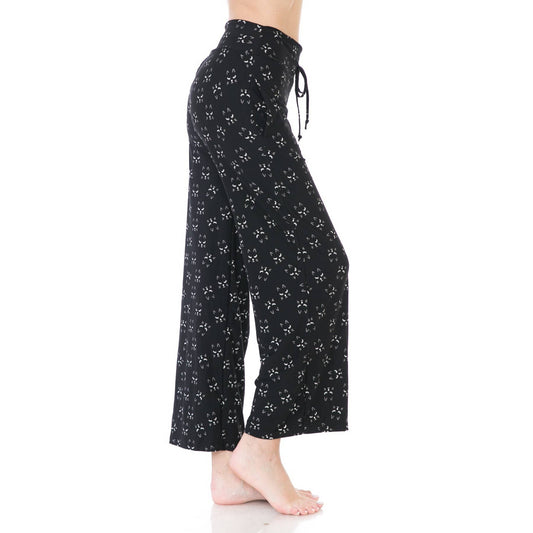 A person stands barefoot in Leggings Depot Buttery Soft Print Pajama Pants, featuring a small white floral pattern and elastic waistband, shown from the side against a white background.