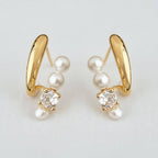 Experience timeless elegance with the Ellemadera Zircon Pearl Dangle Earrings. These earrings feature a graceful curved gold design, each adorned with three radiant white pearls and a sparkling clear zircon gemstone. Perfect for those who appreciate classic sophistication, the earrings are beautifully displayed against a simple white background.