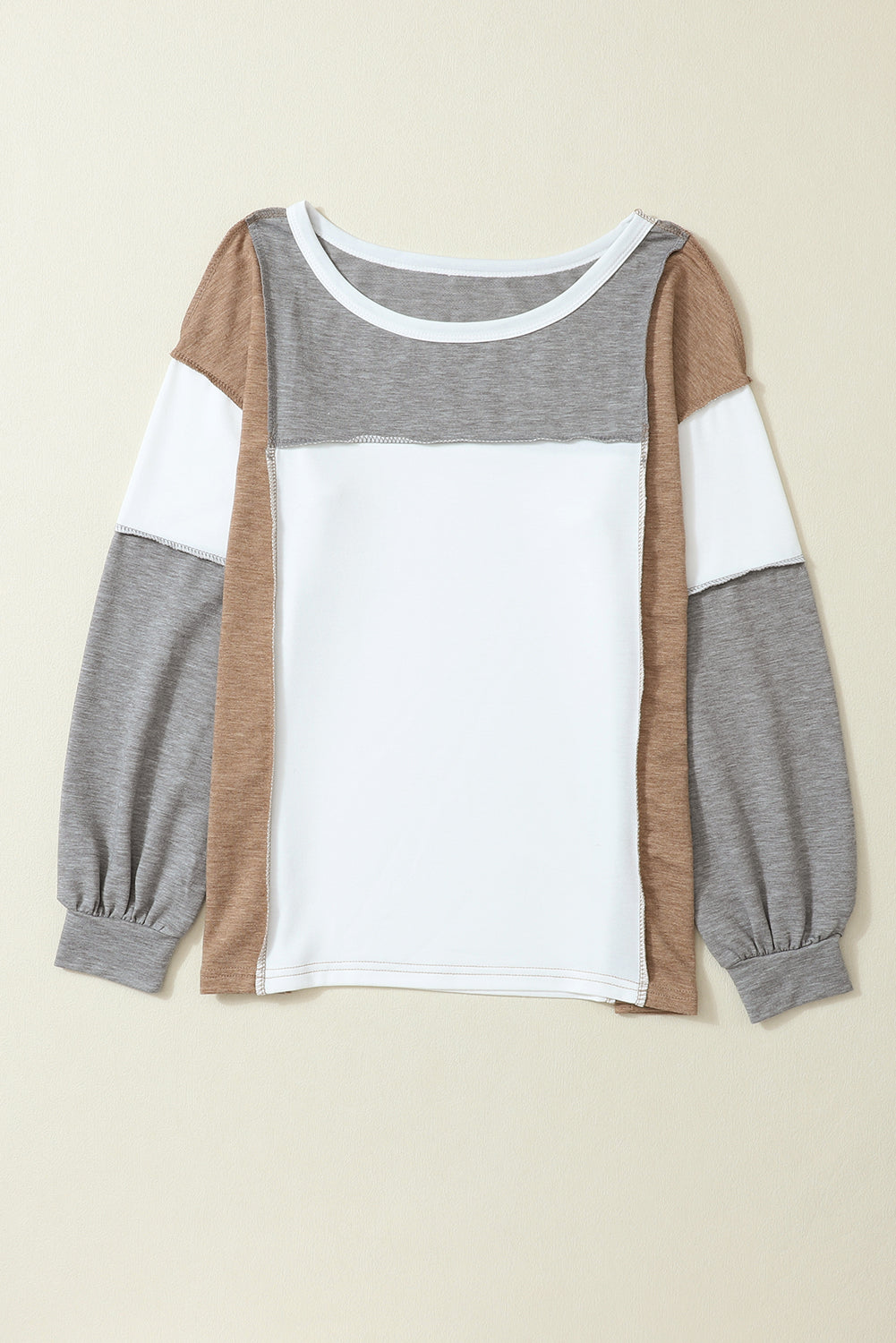 The Khaki Color Block Exposed Seam Long Sleeve Top by Shewin features a white front panel, grey and brown sleeves, and a versatile khaki color palette that seamlessly blends white, grey, and brown sections.