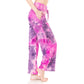 A person, barefoot and seen from the side against a white background, models Leggings Depot Buttery Soft Print Pajama Pants in a pink and purple tie-dye design.