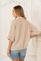 A woman stands indoors facing away, wearing the Sew In Love Relaxed Fit Collared V Notch Neck Striped Top and frayed denim shorts.
