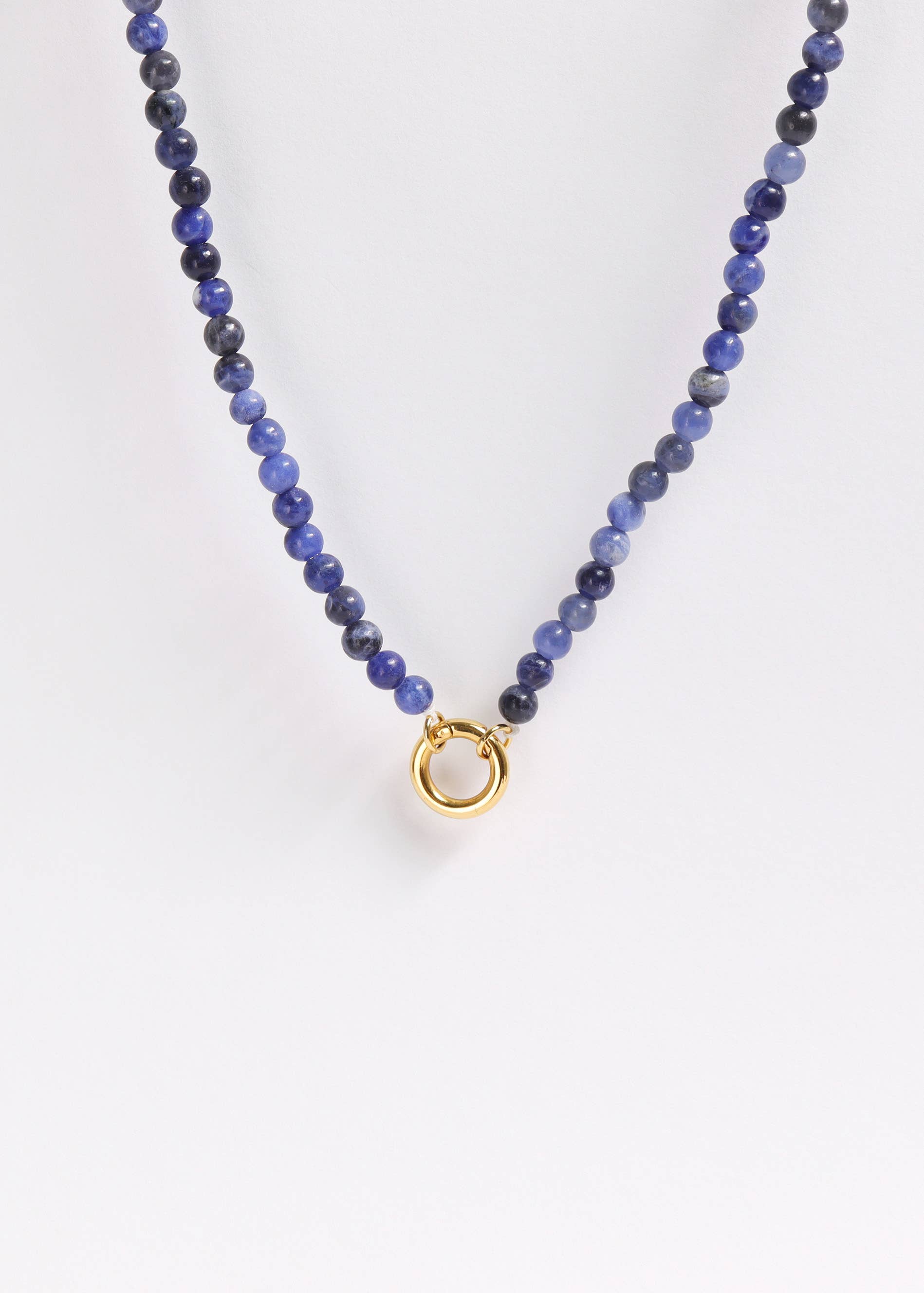 The WJW Semi Precious Natural Stone Charm Keeper Necklace showcases round blue semi-precious stones and is finished with an elegant circular clasp coated in 18K Gold PVD, beautifully presented against a plain white background.