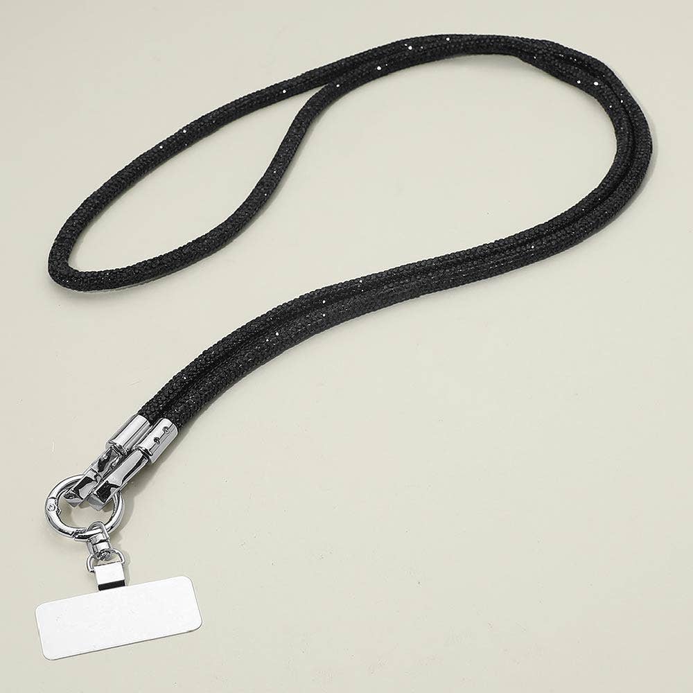 A Rhinestone Phone Lanyard Necklace by Sensibling Corp. with a sleek black strap, silver clasp, and an attached blank rectangular name tag is displayed on a plain light surface.