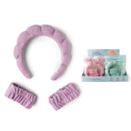 A lavender I Washed Up Like This Super Soft Dryband Set with matching wristbands for washing face, shown alongside a display box containing additional sets in pink and mint green.