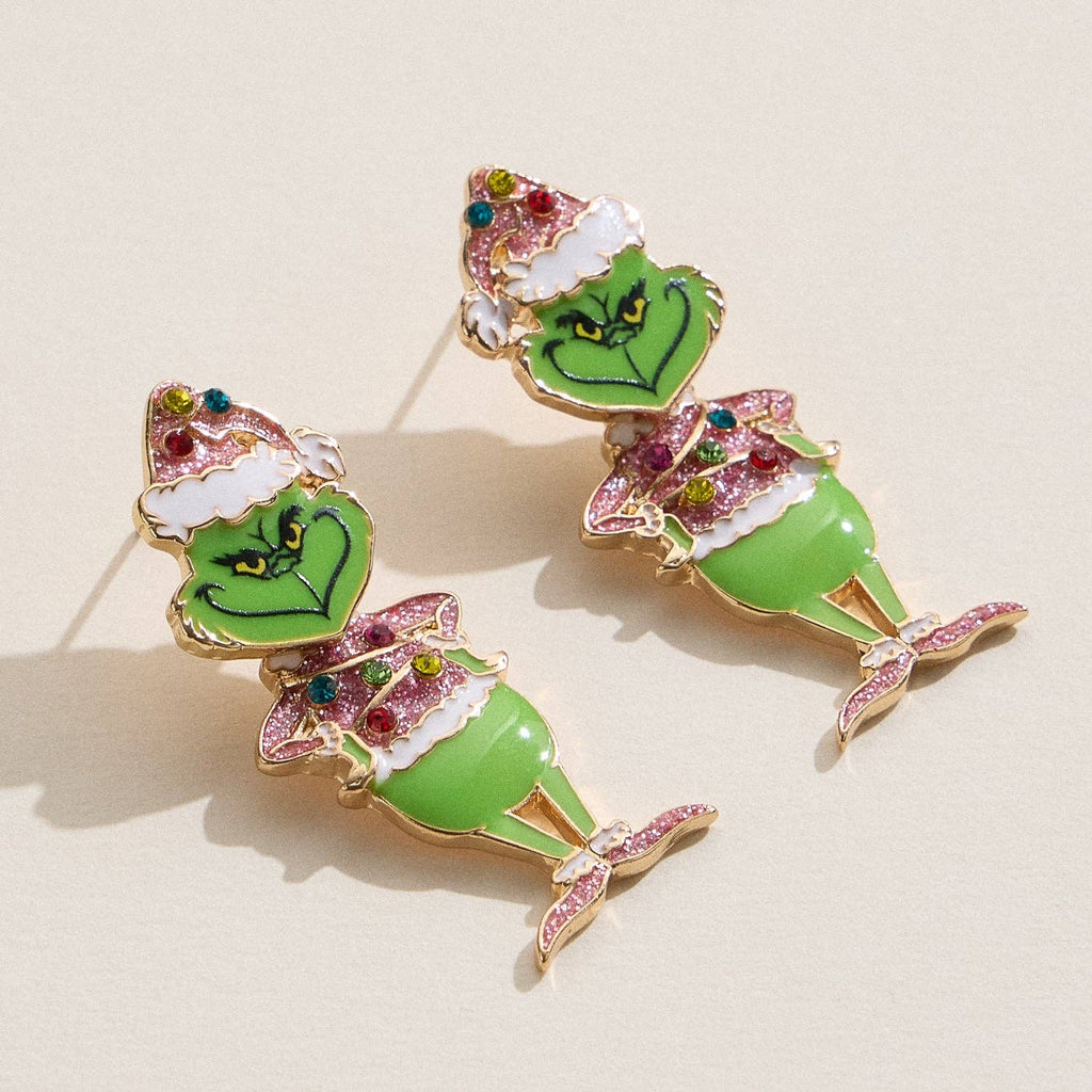Add playful charm to your Christmas look with the Enamel Green Monster Drop Earrings from Lilla Haven—these festive statement earrings feature a glittery holiday character adorned with colorful rhinestones and a Santa hat, perfect for showing off your holiday spirit.