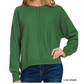 A person wearing a Zenana Viscose Front Seam Round Neck Sweater in dark green with long sleeves and blue jeans, posing with one hand on their hip.