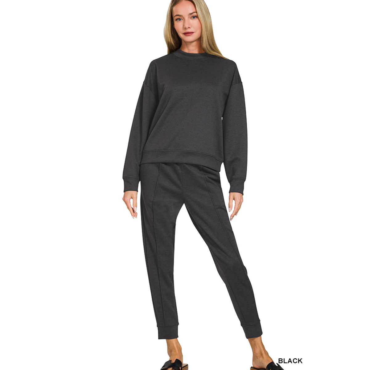 A woman wears the FASHION GO Scuba Fabric Mock Neck Pullover Jogger Set—black long-sleeve sweatshirt and lounge pants—with black slip-on shoes, standing against a plain white background.