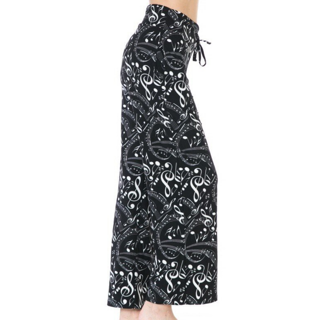 A person wearing the FASHION GO Buttery Soft Pajama Pants with a black and white music note pattern, featuring a drawstring waistband and functional pockets, photographed from the side.