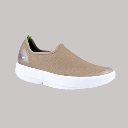 The OOFOS OOMG EASY LOW TAUPE, from OOFOS LLC, offers ultimate comfort with its 4-way stretch design and is showcased with a stylish white sole and a small green tag at the heel against a simple gray background.