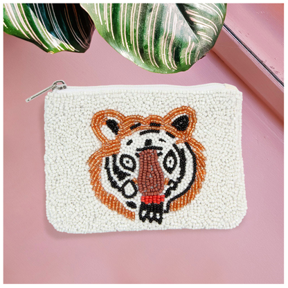 The Seed Bead Accented Mini Pouch Bag Assorted by Wona Trading features a tiger face crafted from seed beads. This stylish white zipper coin pouch makes a perfect gift for fashion-forward friends.