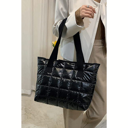 A person wearing a white blazer and beige pants holds the FASHION GO Quilted Shoulder Tote Bag - Assorted Colors, highlighting the style and versatility of this lightweight tote bag with sleek black straps.