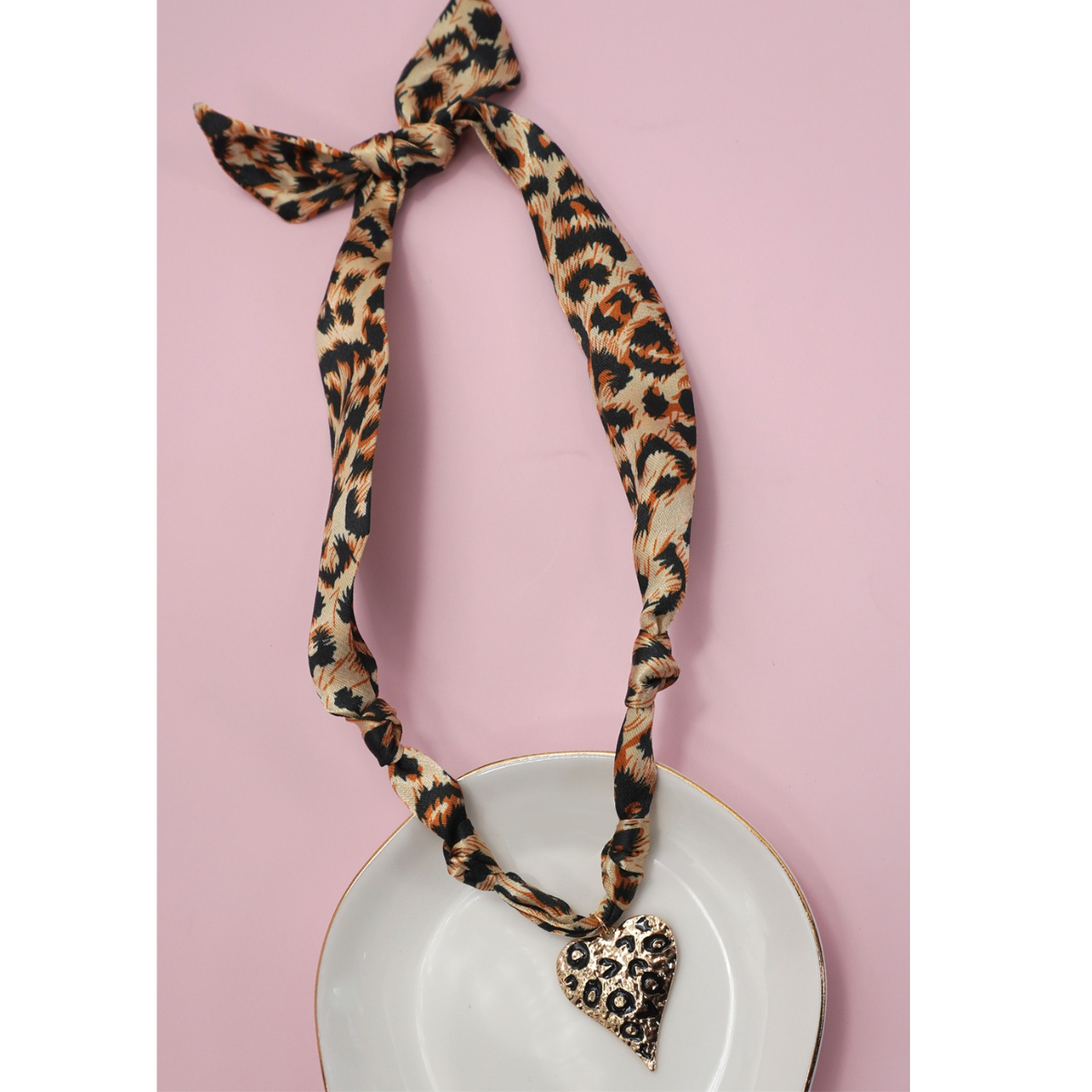 The FASHION GO Handmade Scarf Necklace in assorted colors and patterns is shown on a white plate with a pink background, featuring a chic design with trendy details. Main image