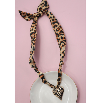 The FASHION GO Handmade Scarf Necklace in assorted colors and patterns is shown on a white plate with a pink background, featuring a chic design with trendy details.