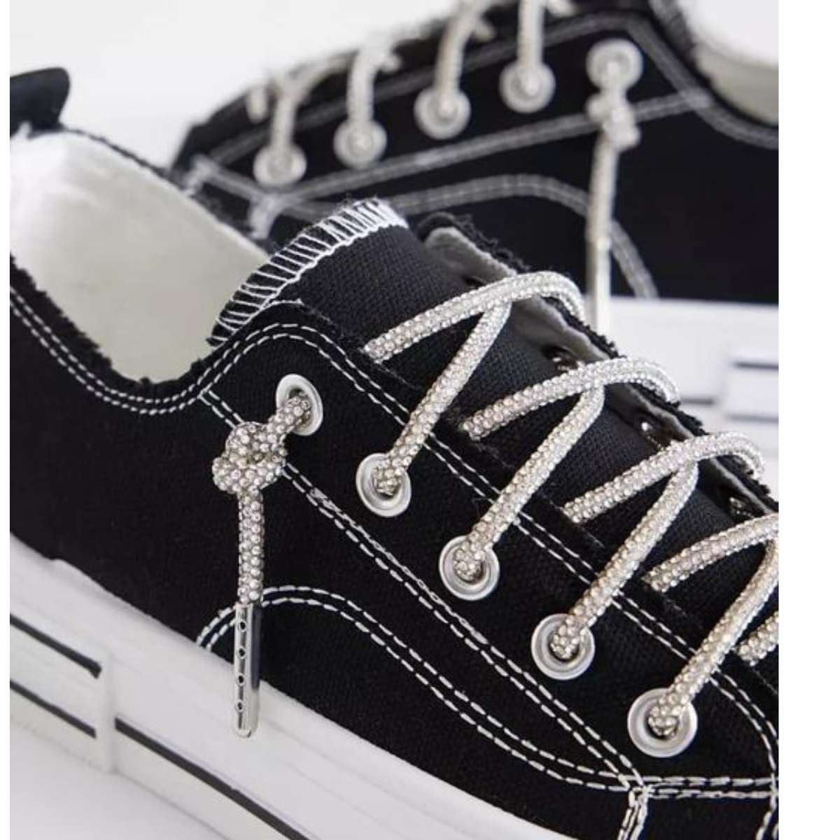 Close-up of a pair of Aman Tennis Shoes in black by VERY G, featuring white stitching, a platform rubber outsole, and clear rhinestone-covered laces.