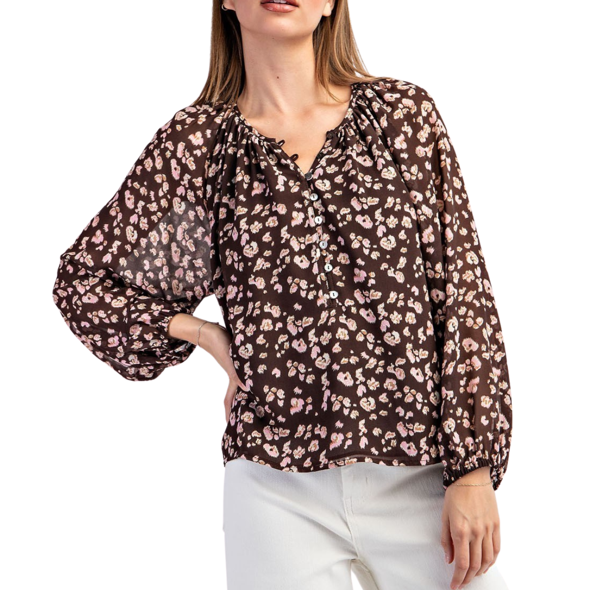 A person wears the Leopard Print Blouse in Brown by FASHION GO featuring a relaxed silhouette and long sleeves, paired with white pants, standing with one hand on their hip.