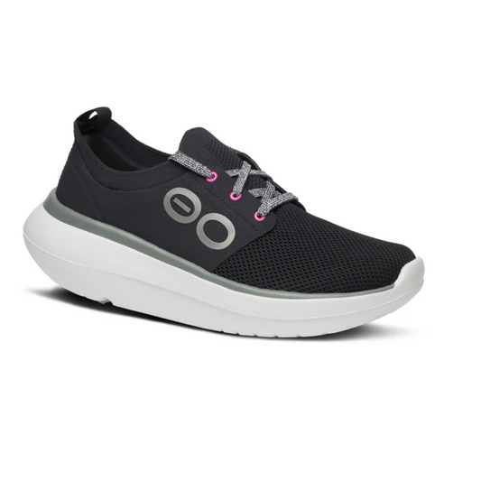 The Oh My Stride in Black/White by OOFOS LLC is a black athletic shoe featuring a white sole, a gray circular logo on the side, and gray-pink laces, designed for both sports and casual wear. It boasts a breathable 4-way stretch fabric for comfort and an antimicrobial footbed to keep your feet fresh all day long.