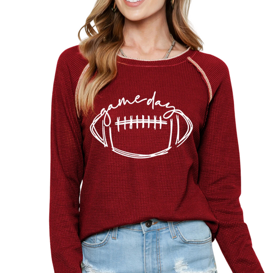 A woman wearing the Shewin Game Day Red Waffle Graphic Contrast Hem Top, paired with light-wash denim shorts.