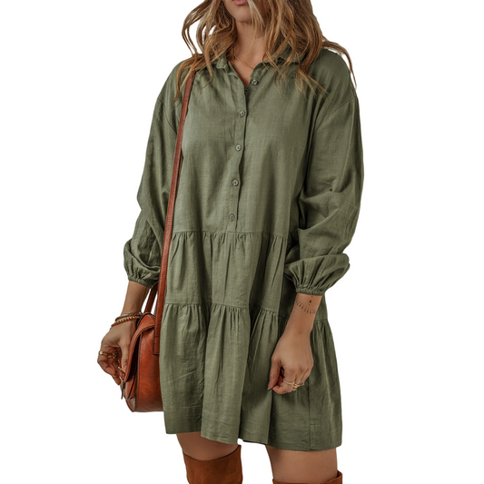 An individual wearing the Shewin Puff Sleeve Tiered Dress in Olive, carrying a brown shoulder bag, and wearing brown knee-high boots.