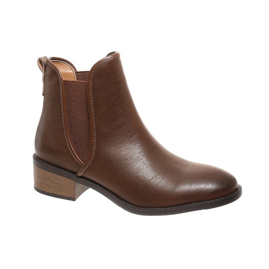 The Jasper Boot in Whiskey Brown by Pierre Dumas, produced by OLEM SHOE CORP, features a brown leather ankle design with a low block heel and stretch-textured side panels. These slip-on style booties offer both comfort and elegance.