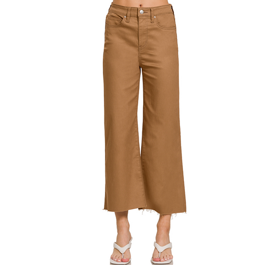 A person wearing High Rise Colored Crop Pants in Camel by Zenana with a raw hem, paired with white heeled sandals.