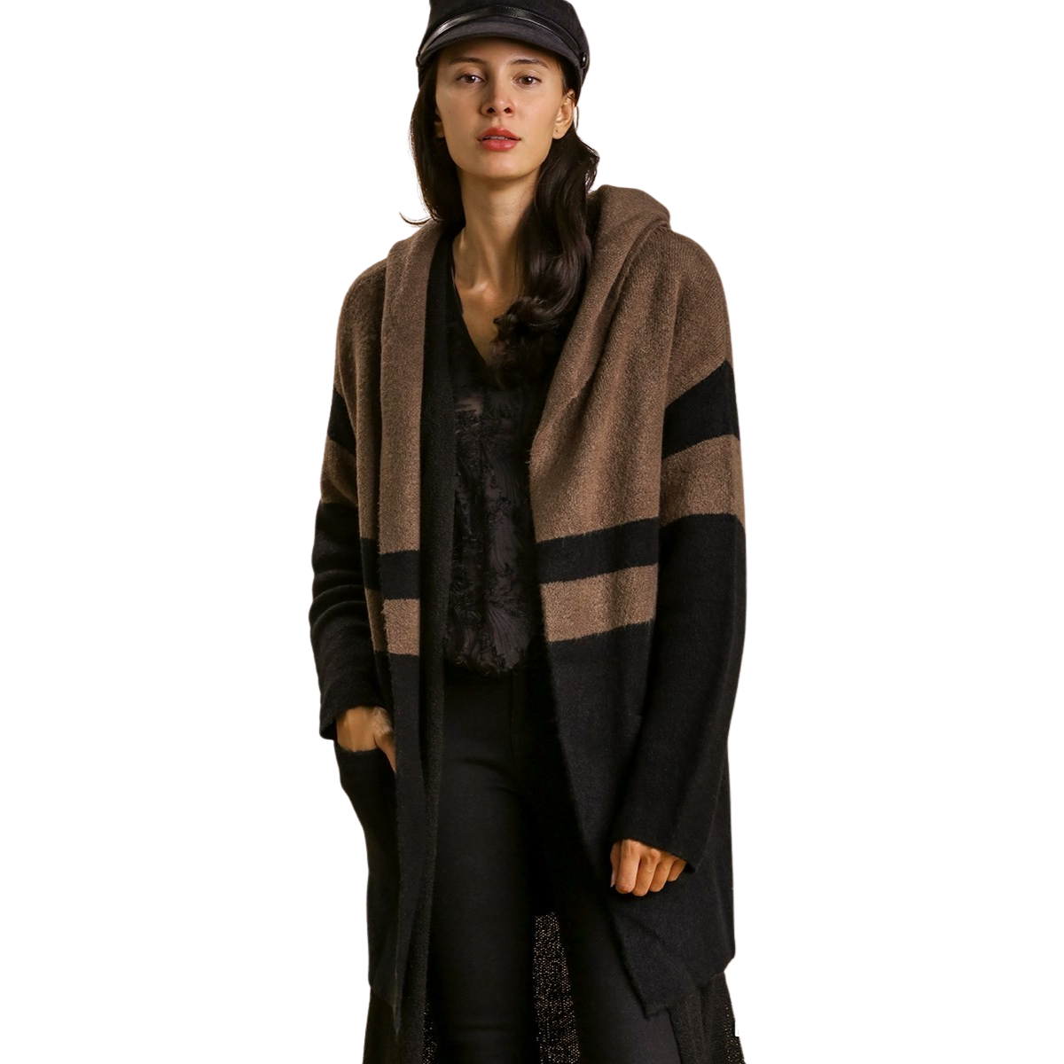 A woman models the Umgee Color Block Cardigan Sweater with Hoodie & Side Pockets in black and brown, styled with black pants and a black cap, standing against a white background.