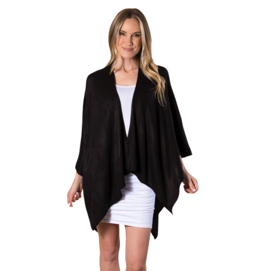 A woman in a white dress and the Cardi Wrap - Black by Ganz Inc stands against a white background, exuding an elegance that makes for a great gift.