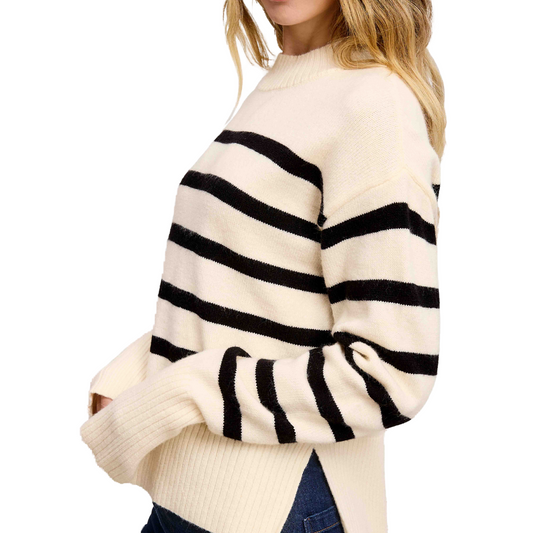 A side view of an individual wearing the FASHION GO Super Soft Striped Mock Neck Sweater in cream with black stripes, paired with blue jeans, highlights a relaxed fit that emanates effortless style.