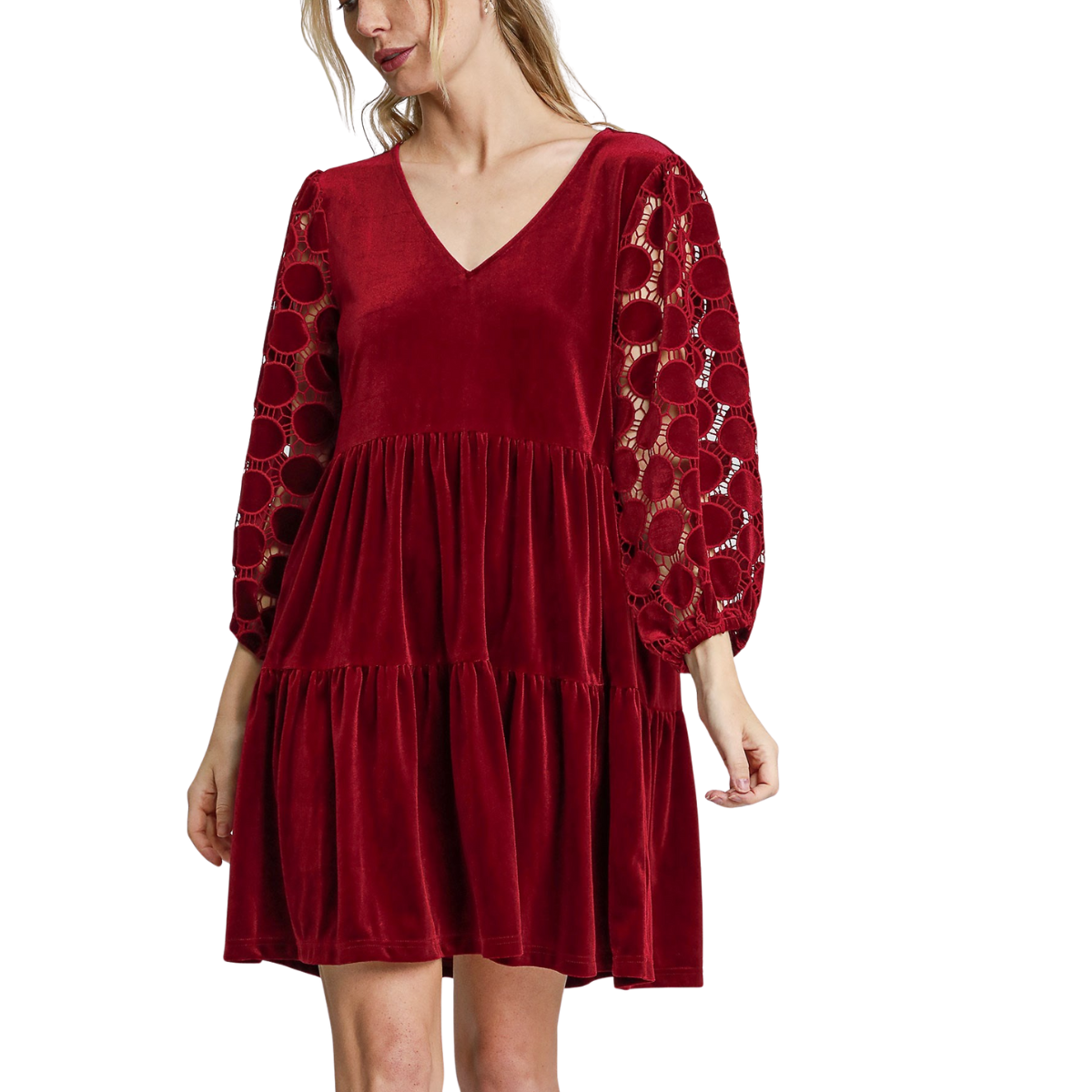 A woman wears the Umgee Tiered Velvet Mini Dress in Wine, featuring a V-neckline, tiered skirt, and three-quarter polka dot lace sleeves with circular cut-outs. Main image