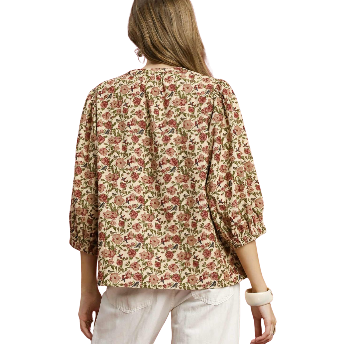 A woman models the Umgee Vintage Floral Pintuck Blouse with three-quarter sleeves and white pants, seen from the back against a white background.
