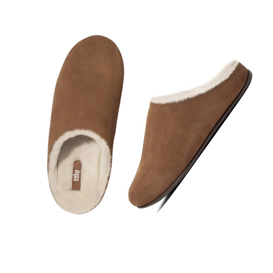 The Chrissie Shearling Slipper in Tan by FITFLOP USA LLC, featuring a brown suede exterior and a cozy white fleece lining, is shown from top and side views, making it ideal for comfortable lounging.