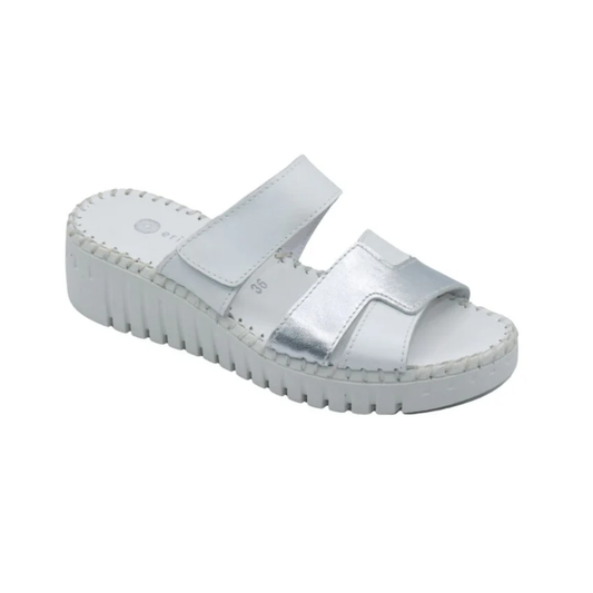 The Darien Leather Sandal in White and Silver by Laurevan Shoe Corp features two wide straps, a thick ridged sole, and a cushioned footbed, shown against a plain white background.