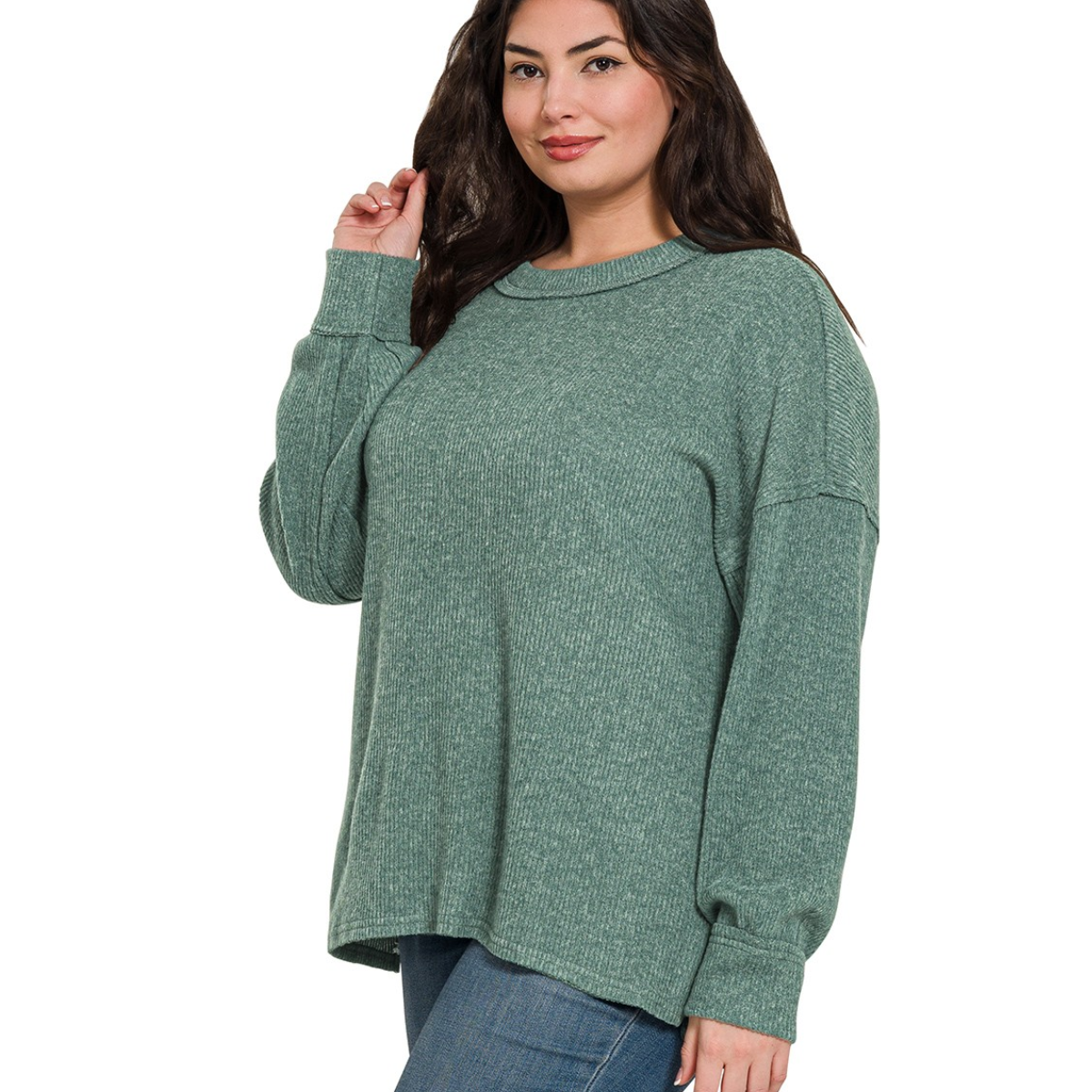 A woman wears the Zenana Brushed Ribbed Hacci Drop Shoulder Sweater in green with blue jeans, posing against a plain white background.