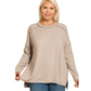 A woman with long blonde hair models the Zenana Soft Melange Hacci Exposed Seam Hi-low Tee, paired with blue jeans, against a plain white background.