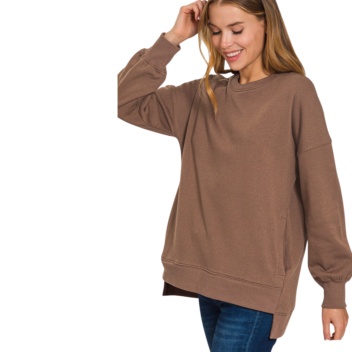 A woman smiles against a white background, wearing the Zenana Fleece Hi-Low Hem sweatshirt with blue jeans, one hand touching her head.