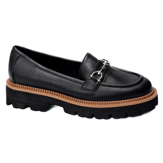 Introducing the Brownie Points Lug Sole Loafer in Black by Corky's, featuring a stylish brown chunky sole and a chic silver chain buckle detail.