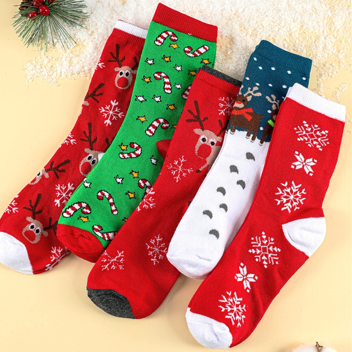 The 5 Pairs/Set Christmas Cartoon Soft Socks Set from FASHION GO, showing off charming reindeer, snowflakes, and candy cane designs, are artfully arranged on a snowy backdrop. These warm and cozy socks are an ideal gift for your loved ones this holiday season.